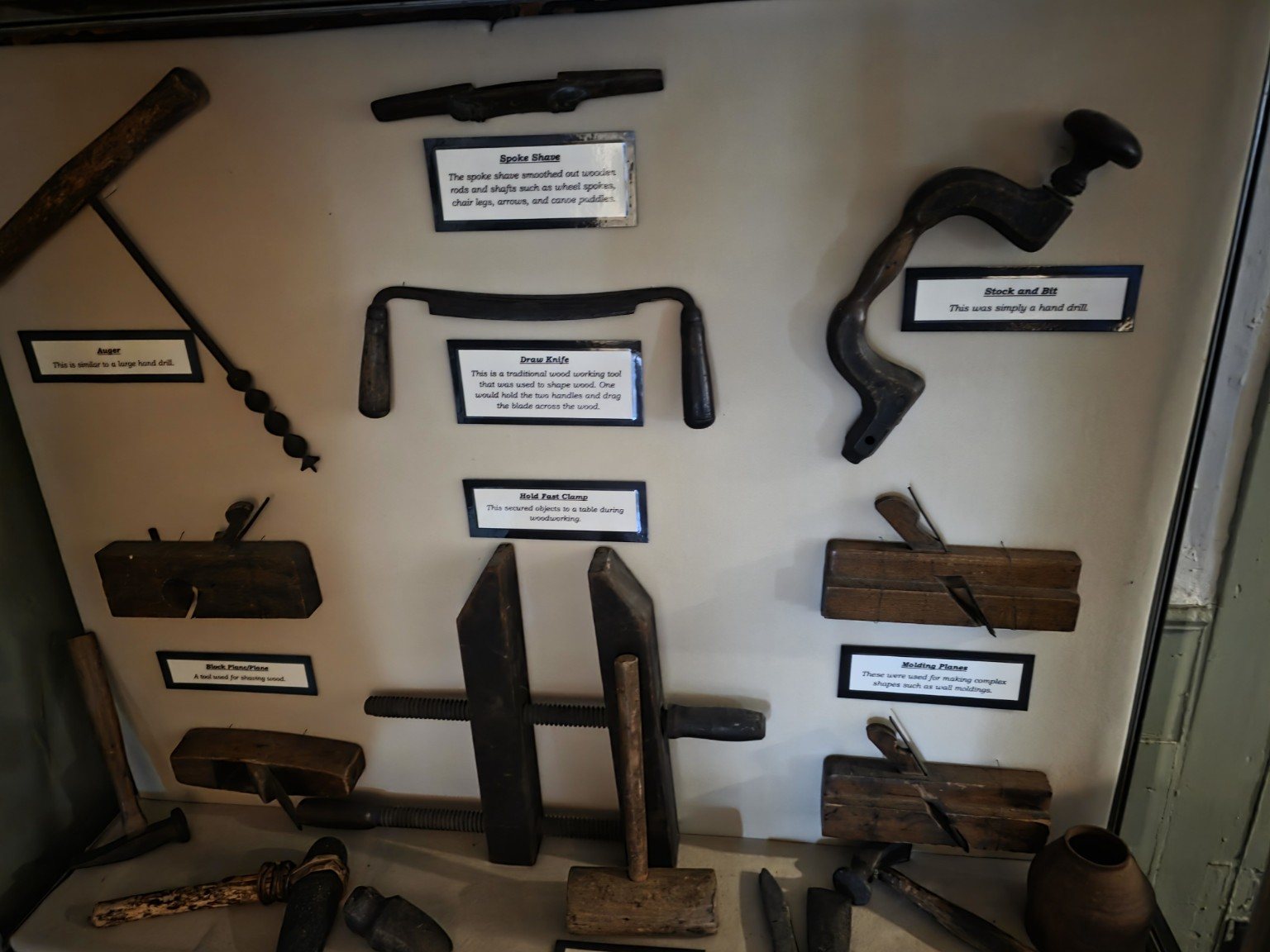 Display of historic hand tools including planes, auger, drawknife, and brace