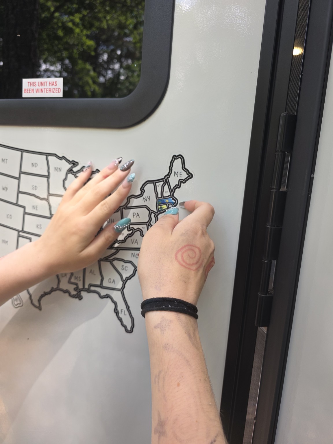 Billie carefully placing the Massachusetts sticker on Trail Tater's travel map